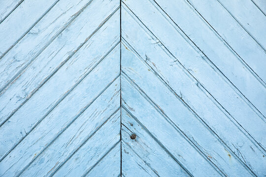Weathered pale blue wooden door with diagonal planks and a rustic painted texture