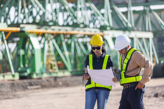 Engineers Reviewing Blueprints Together at Railway Bridge Construction Site