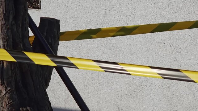 Yellow and black caution tape against white wall