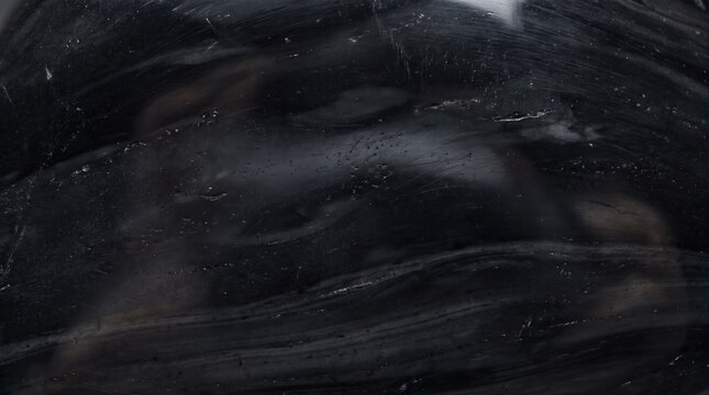 Macro view of a polished black obsidian stone, featuring swirling grey mineral veins and a smooth, reflective surface texture
