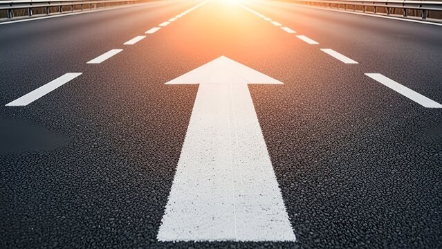 Asphalt highway arrow symbol pointing forward with bright sunrise lighting marking strategic business direction and pathway perspective