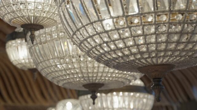 Rows of round crystal chandeliers glowing under a woven bamboo ceiling at a wedding venue.