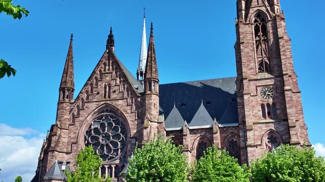 Green treetops framing red sandstone church and spires in Strasbourg, France