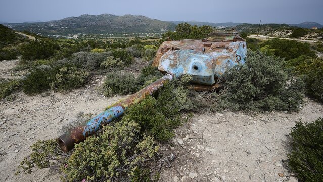 A rusty tank lies in the middle of a barren landscape with green plants, Anthony Quinn Bay, Vagies Bay, Rhodes, Dodecanese, Greek Islands, Greece