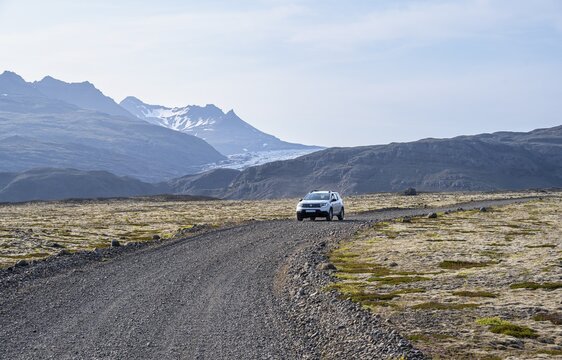 Car driving on gravel road, mountainous landscape, Iceland