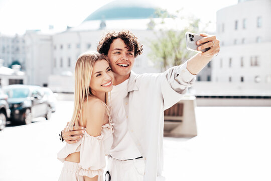 Young smiling beautiful woman and her handsome boyfriend in casual summer clothes. Happy cheerful family. Female having fun. Couple posing in the street background at sunny day. Take selfie