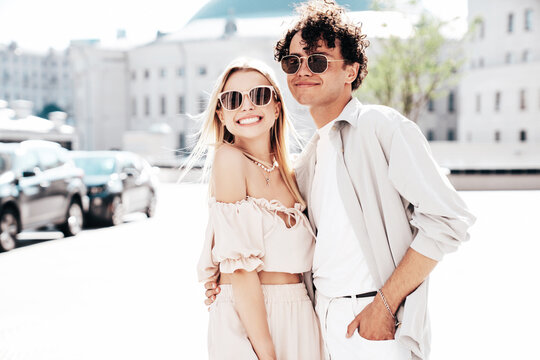 Young smiling beautiful woman and her handsome boyfriend in casual summer clothes. Happy cheerful family. Female having fun. Couple posing in the street background at sunny day. In sunglasses