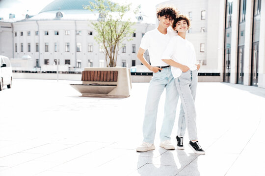 Young smiling beautiful woman and her handsome boyfriend in casual summer white t-shirt and jeans clothes. Happy cheerful family. Female having fun. Couple posing in street at sunny day. Full length