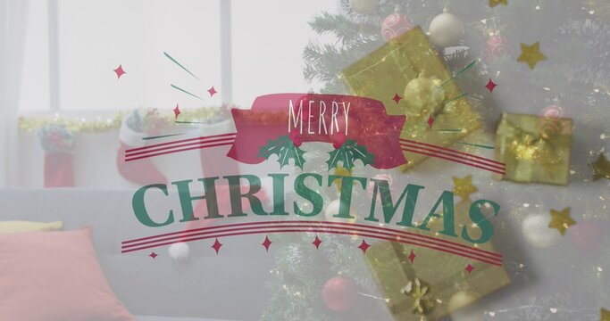 Pink ribbon displaying MERRY above green CHRISTMAS lettering with holly sprigs near blurred tree