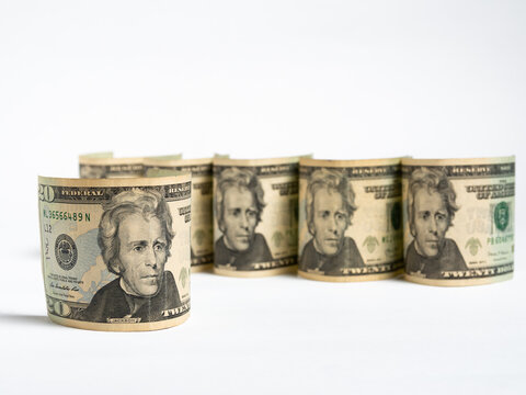 Rolled Twenty Dollar Bills Arranged in a Row on a White Background