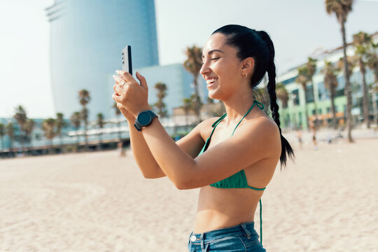 Smiling young woman using her smartphone at the beach