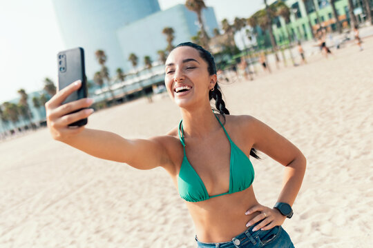 Smiling young woman using her smartphone at the beach
