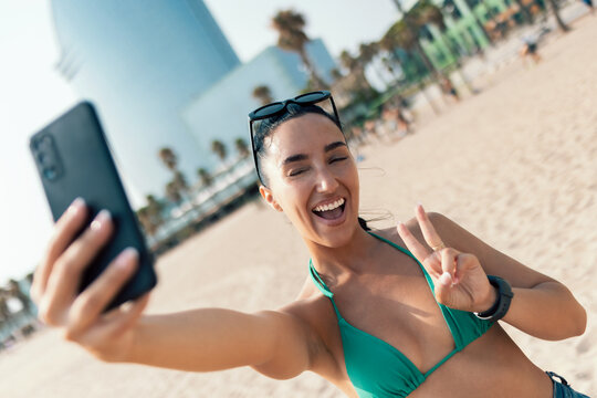 Smiling young woman using her smartphone at the beach
