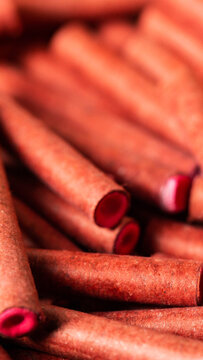 Macro close-up detail of numerous small cylindrical red objects, likely firecrackers or pyrotechnic fuses, showing rough paper texture and vibrant internal color, vertical photo