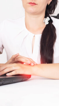 Young adult female experiencing wrist pain while working on laptop keyboard, hand on wrist showing discomfort from repetitive strain injury, medical problem, work related issue, vertical photo, carpal