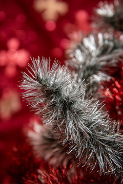 Tinsel in shiny silver with red highlights stands out against bright red background for festive Christmas tree decoration