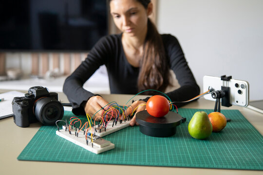 Close up of female hands adjusting electronics for a DIY smartphone AI camera object recognition tech project.