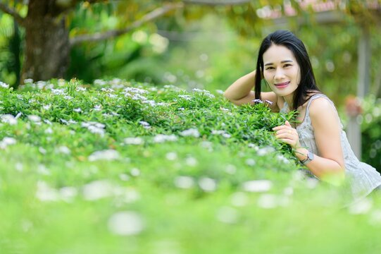 Young Woman Posing in Lush Green Garden Among Beautiful Flowers