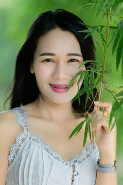 Young Woman Smiling with Green Background and Bamboo Leaves