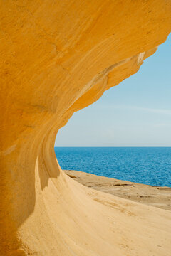 Wind-Eroded Golden Sand Wave Limestone Rock Structure Creating an Organic Curve Against the Deep Blue Sea Horizon, Gozo, Malta