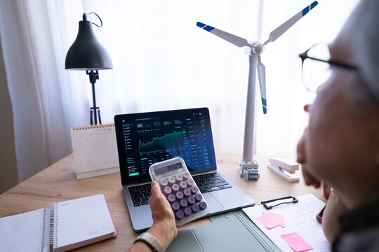 White person working with calculator and financial data on laptop
