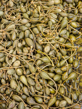 Close up view of pickled caperberries with long stems in brine solution