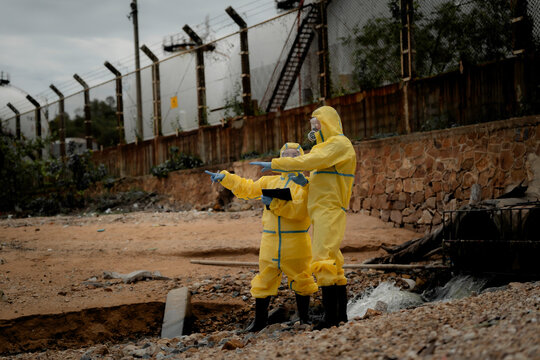 Hazardous chemical contamination inspection concept. Environmental scientists in protective suits collecting polluted water samples near industrial wastewater area. pollution, hazmat, safety,