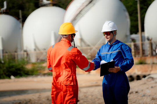  Industrial engineering and workplace safety concept. Two energy plant workers communicating during inspection at a gas storage facility outdoors. engineer, industry, safety, teamwork, energy