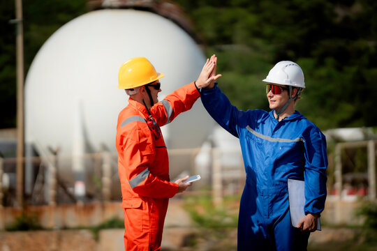  Industrial engineering and workplace safety concept. Two energy plant workers communicating during inspection at a gas storage facility outdoors. engineer, industry, safety, teamwork, energy