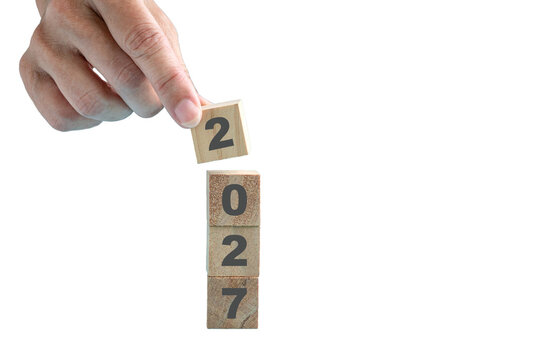 Hand Placing Wooden Block for 2027. Isolated on transparent background.