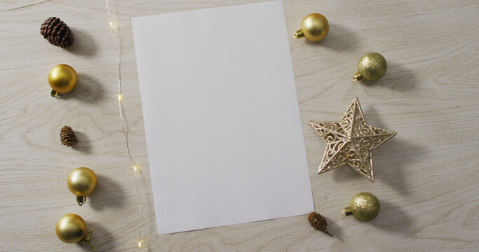 Image of christmas decorations with white card and copy space on wooden background