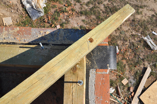 Roof wooden beam waterproofing on brick wall during roofing construction