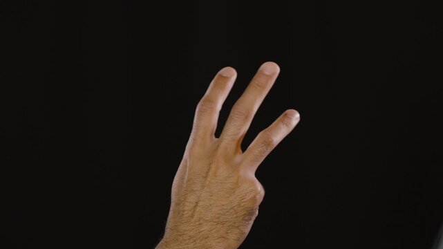 Male hand counting down from five to zero using fingers against an isolated dark black backdrop. Useful for intro sequences, sports, education, and launch concepts.