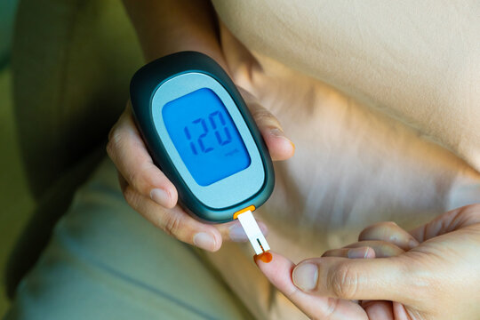 Woman's hands checking diabetes and hyperglycemia with digital blood sugar meter. Healthcare and medical concept	