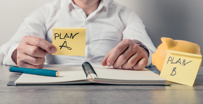 Businessman hand writing plan A  plan b with piggy bank and notepad
