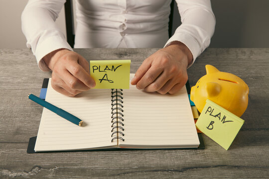 Businessman hand writing plan A  plan b with piggy bank and notepad