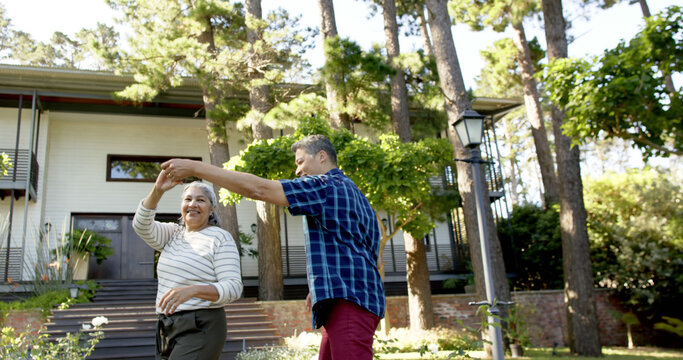 Happy senior couple dancing in sunny garden