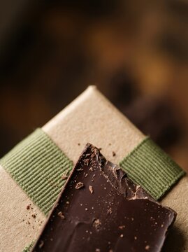 Dark chocolate piece resting on a brown craft paper gift box with a green ribbon