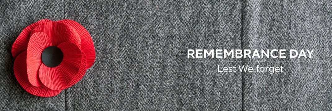 Red poppy flower on grey herringbone fabric background with Remembrance Day text, commemorative symbol for Veterans Day
