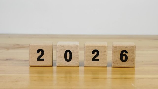 Flipping hand of cubes wooden 2026 to 2027 new year on table wood white background.  
Year 2026 2027 block wood christmas and happy new year concept.