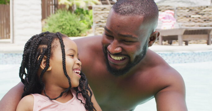 Portrait of happy african american father and daughter having fun in swimming pool