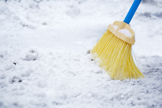 Removal fresh snow with yellow broom sweeping at winter, during the day.
