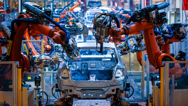 Automated robotic arms welding car body on assembly line in modern automotive factory, smart manufacturing industry