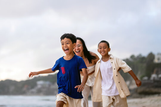 Asian single mother enjoying a summer travel getaway on the beach with her children