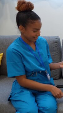 Young latina home health nurse smiling while playing a card game during a patient visit in a bright living room