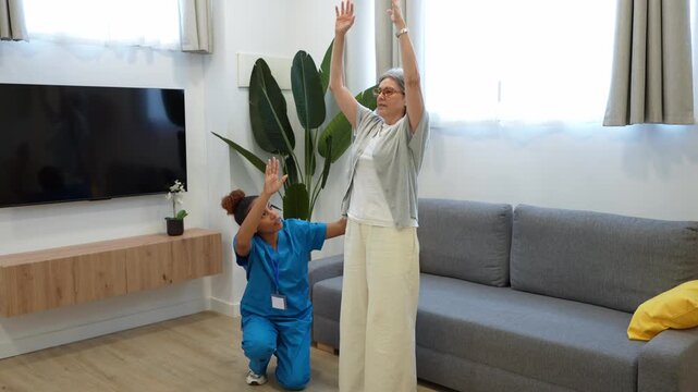 Hispanic female nurse assisting an elderly woman doing gymnastics exercises in living room during home visit