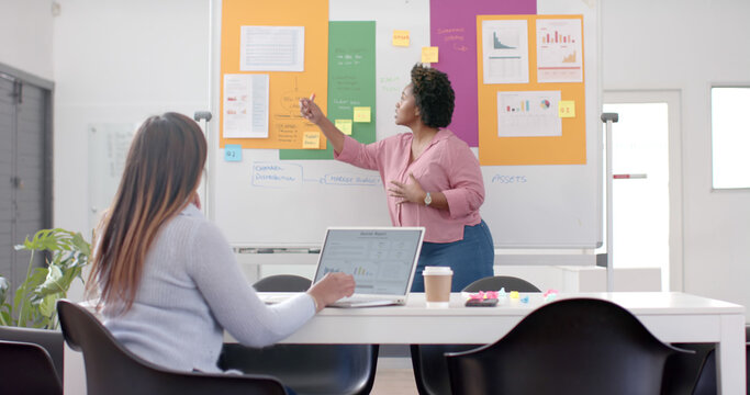 African american casual businesswoman making presentation using whiteboard in office