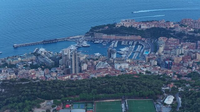 Port hercule in monaco, viewed from above during twilight, with luxury buildings lining the mediterranean coastline and yachts filling the harbor beneath the evening sky