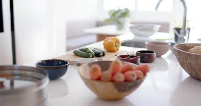 Camera gliding across kitchen counter revealing carrots, zucchini and red onion near sink