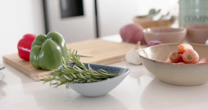 Camera gliding right across marble counter revealing rosemary peppers radishes and mint compost bin